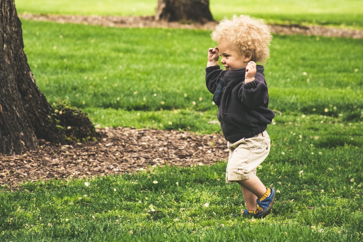 Happy toddler running in the park reminds us of positive things to say to a child to help them grow