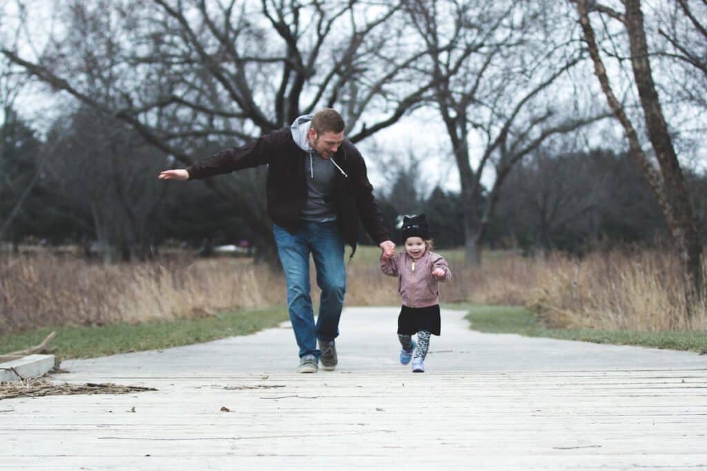 Dad is running with daughter in the park