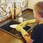 Young boy in the kitchen washing a plate