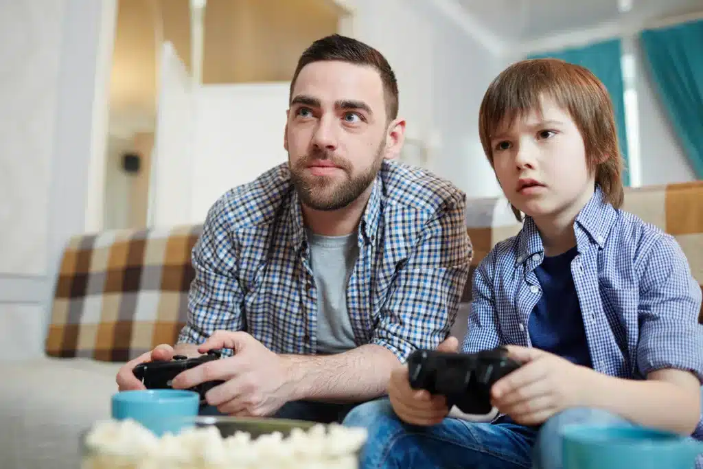 Father and son holding controllers playing a video game on the console
