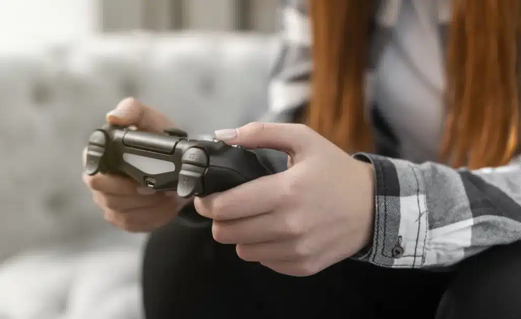 Teen with red hair holding a controller playing a video game
